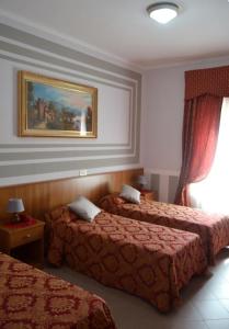 a hotel room with two beds and a painting on the wall at Hotel Facioni in Pomezia