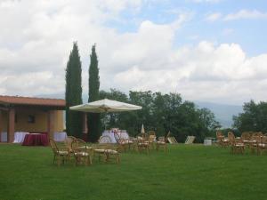 een groep tafels en stoelen met een paraplu bij Agriturismo Il Palazzo in Pergine Valdarno