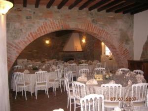 een kamer met witte tafels en stoelen en een bakstenen muur bij Agriturismo Il Palazzo in Pergine Valdarno