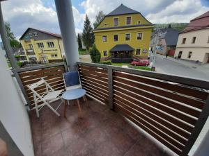 un balcón con una silla y una casa amarilla en Apartmány AMADE Jeseníky, en Vrbno pod Pradědem