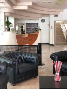 un hall avec des canapés en cuir noir et un bar dans l'établissement Hotel Artide, à Rimini