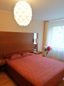 um quarto com uma cama grande e um lustre em Amber apartamentai em Druskininkai