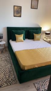 un letto verde con cuscini gialli in una stanza di SUMERLAND BARI Apartment a Mamaia