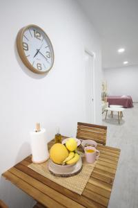 une table avec une assiette de fruits et une horloge sur le mur dans l'établissement Estudio céntrico, à Conil de la Frontera
