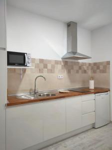 - une cuisine blanche avec évier et four micro-ondes dans l'établissement Estudio céntrico, à Conil de la Frontera