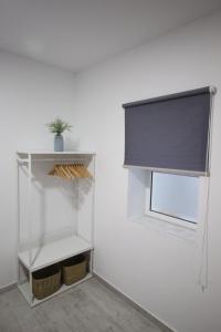 Cette chambre blanche dispose d'une fenêtre et d'une étagère. dans l'établissement Estudio céntrico, à Conil de la Frontera