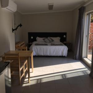 a bedroom with a bed and a table and a window at One One Five Albrecht Street in Bloemfontein