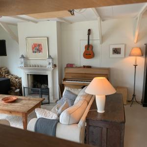 een woonkamer met een bank en een piano bij Holiday home at the water, fire place, boat and SUP rent, near Amsterdam in Aalsmeer