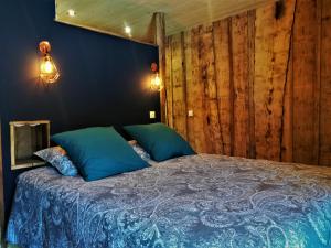 a bedroom with a bed with blue sheets and wooden walls at Domaine Moulin la Place in Saint-Martin-de-Saint-Maixent
