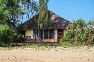 ein Haus mit einem Strohdach am Strand in der Unterkunft Saadani Safari Lodge in Saadani