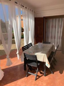 a dining room with a table and chairs and curtains at Trilocale Vignola Mare in Aglientu
