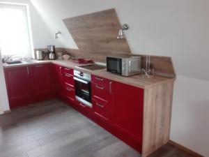cocina con armarios rojos y microondas en Finnhütte Bernstein, en Gager