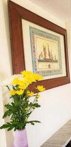 a vase with yellow flowers in front of a picture at Kastro Hotel in Spetses
