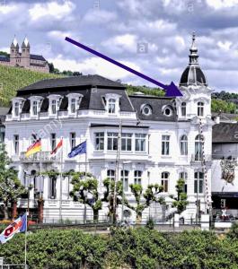 ein großes weißes Gebäude mit spitzem Dach in der Unterkunft Villa Sturm Rüdesheim am Rhein in Rüdesheim am Rhein