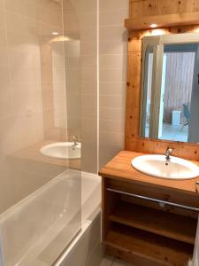 a bathroom with a tub and a sink and a mirror at Appartement 4 personnes Les Orres 1800 au pied des pistes in Les Orres