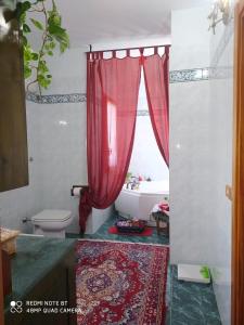 La salle de bains est pourvue d'un rideau de douche rouge et d'une baignoire. dans l'établissement B&B Lo Smeraldo, à Grottaglie