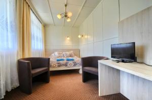 ヴィスワにあるOśrodek Wczasowy Kłosのベッド1台、椅子2脚、テレビが備わる客室です。