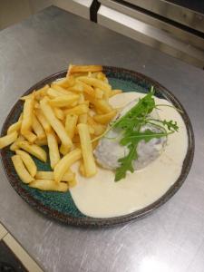 a plate of food with french fries on a table at Les Remparts in Montreuil-sur-Mer