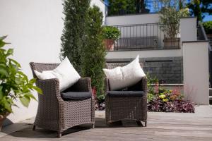 two wicker chairs with pillows sitting on a patio at Strandhotel Fontana in Timmendorfer Strand