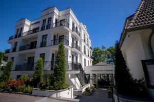 a white building with plants in front of it at Strandhotel Fontana in Timmendorfer Strand
