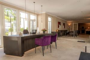 a large living room with purple chairs and a bar at Strandhotel Fontana in Timmendorfer Strand