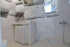 baño con lavabo y aseo y ventana en Tranquil cottage, en Agios Sostis