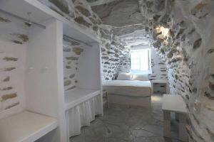 1 dormitorio con cama y pared de piedra en Tranquil cottage, en Agios Sostis