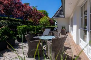 a patio with wicker chairs and a glass table at Strandhotel Fontana in Timmendorfer Strand