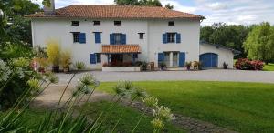 een groot wit huis met blauwe ramen en een tuin bij BIDACHUNA in Saint-Pée-sur-Nivelle