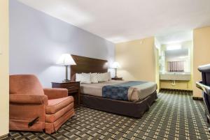 a hotel room with a bed and a chair at Rodeway Inn Lincoln West - University Area in Lincoln +18 photos