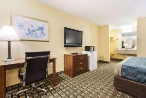 a hotel room with a bed and a desk and a television at Rodeway Inn Lincoln West - University Area in Lincoln