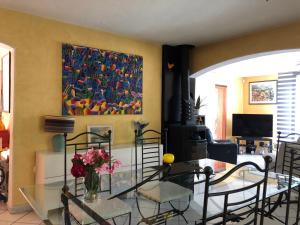 a dining room with a glass table and a painting at Chambres Table d'hotes Carpe diem in Villeneuve-la-Rivière