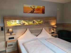 a bedroom with a white bed with a picture on the wall at Hotel Bigger Hof - Wirtshaus Platzhirsch am Jahnplatz in Olsberg