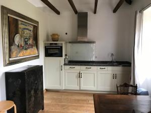 a kitchen with white cabinets and a painting on the wall at Residence Le petit paradis - La petite maison in Labastide-Rouairoux