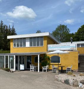 a yellow building with a table and chairs at Aa Strand Camping in Ebberup