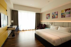 Habitación de hotel con cama, escritorio y TV. en Higher Hotel en Bandar Seri Begawan
