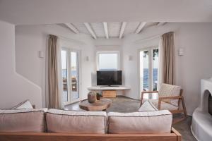 a living room with a couch and a tv at Villa Santa Katerina - Sea View & Outdoor Hot Tub in Platis Yialos Mykonos