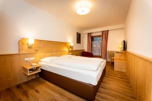 ein Hotelzimmer mit einem großen Bett und einem Schreibtisch in der Unterkunft Hotel Krone in Matrei am Brenner