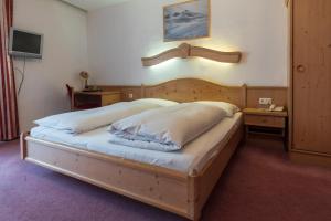 Schlafzimmer mit einem großen Bett mit einem Kopfteil aus Holz in der Unterkunft Hotel Krone in Matrei am Brenner