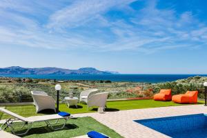 a patio with white chairs and a swimming pool at Nereid Villa, summer feeling, By ThinkVilla in Episkopí- Rethimno