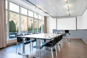 een conferentieruimte met een grote tafel en stoelen en een wit scherm bij Hapimag Ferienwohnungen Interlaken in Interlaken