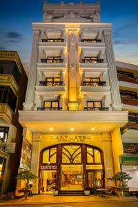 a tall white building with a store front at Hanoi Dalvostro Valentino Hotel & Spa in Hanoi