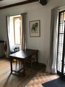 a dining room with a wooden table and two windows at Residence Le petit paradis - La petite maison in Labastide-Rouairoux