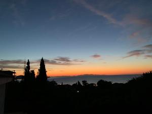 a sunset over the ocean with trees in the foreground at Villa Riverside in Platána