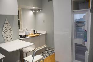uma pequena cozinha com frigorífico, mesa e cadeiras em Residence sur Cour em Paris