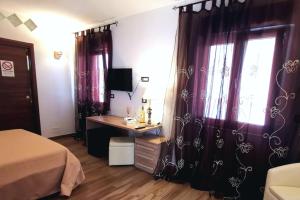 een slaapkamer met paarse gordijnen, een bureau en een raam bij Sunset Bed & Breakfast in Peschici