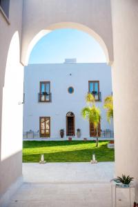 un arco que conduce a un edificio blanco con un patio en Baglio La Riserva en Scopello