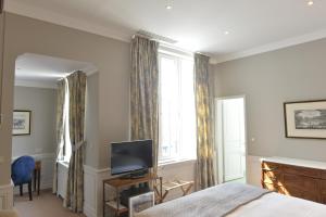 a bedroom with a bed and a tv and a window at Hôtel de Londres in Fontainebleau