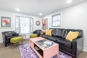 a living room with a black leather couch and chairs at Folly Vacation Beautiful Beach Cottage 209-A in Folly Beach