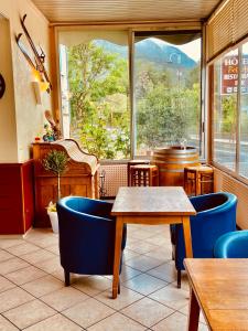 un restaurant avec des chaises bleues, une table et une fenêtre dans l'établissement Hôtel Bel'Air, à Jausiers